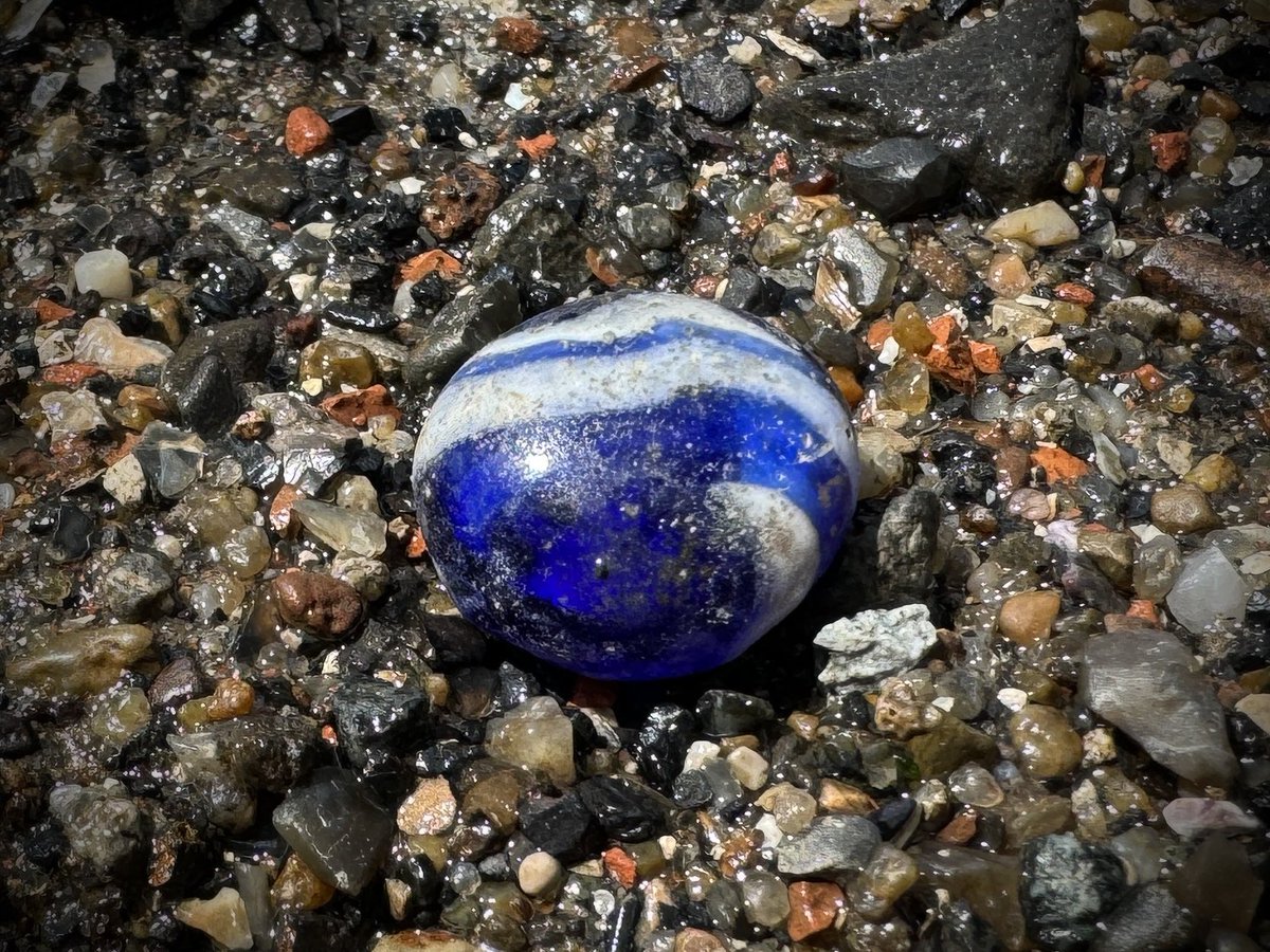 I think this is a post medieval game piece, it’s flat on one side and domed on top. Glass Roman game pieces are found on the foreshore but they are usually plain black or white and I’m quite confident this swirly blue isn’t Roman

Either that or it’s a squashed marble #mudlarking