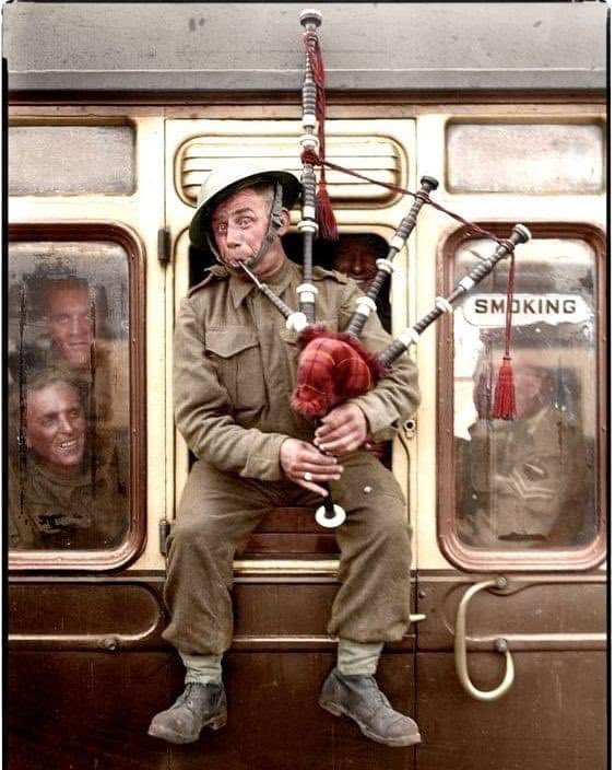 A Scottish soldier plays the bagpipes in the window of a train homebound after being successfully evacuated from Dunkirk late May or early June 1940