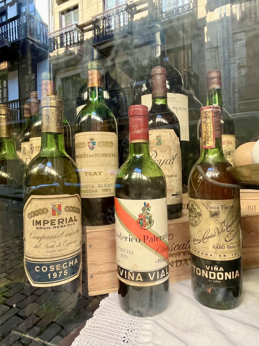 Botellas de #vino con casi medio siglo de vida. 
Añadas históricas. Bodegas legendarias. Todas ellas expuestas a la vista del viandante con una cuidada disposición, el peso, el pimentón, especias…el sabor de lo añejo. Fragmentos de historia. Escaparates que huelen. 
➕👇