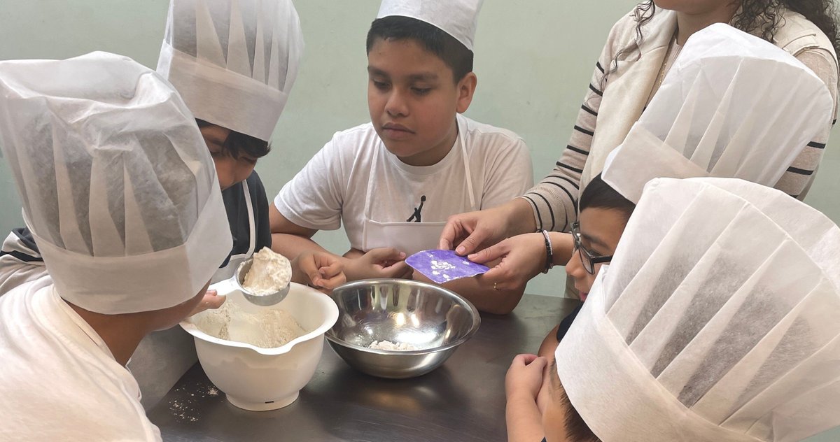 P.S. 4 students had a blast at Young Chefs Academy, diving into the science of cooking! They made their own breadsticks, wore chef hats, and explored how recipes connect us. Inspired by "Tomatoes for Neela," they discovered the joy of creating and sharing food together.