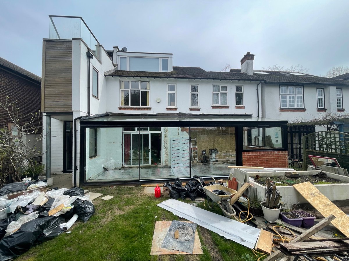 A large glass box extension now finished on site in London. The glass box includes a full glass roof and sides with minimal windows sliding doors in the rear elevation, all finished in RAL 9005. Read about designing a glass extension here: iqglassuk.com/news/the-anato…