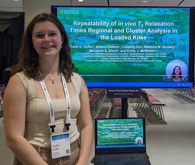 Student Katie Sofko standing in front of a power point slide at a research conference.