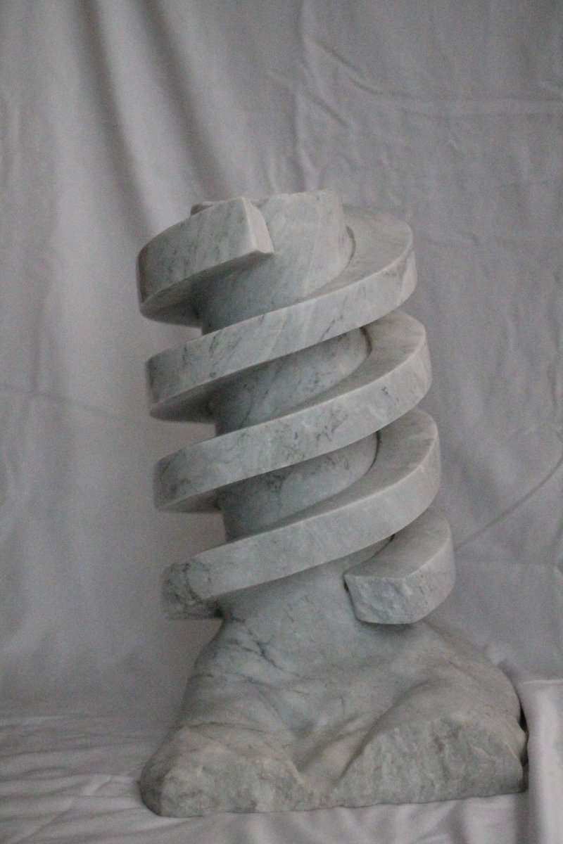GreenGolemMag's tweet photo. “Golem DNA” by Hal Goldberg

The double helix DNA of the Golem is now preserved in marble, and will re-create a new Golem whenever the Jews are in jeopardy.  On the top of the double helix is carved the word “Emet”, “truth” in Hebrew.

In the original story of the Golem of Prague, the Golem was activated by inscribing “Emet” on its forehead. To deactivate the Golem, the letter aleph was removed, transforming the word “truth” to the word “death”.

(2001) White Carrara Marble 17" x 11" 13"

Hal has been a marble sculptor for over 50 years. He studied at the Laguna College of Art and Design (Laguna Beach, California)  and at the Art Students League (New York), but is primarily self-taught. He carves directly in the stone.

The purpose of Hal's sculptures is to make people think long and hard about the Holocaust. The sculptures are dedicated to one of the most important lessons of the Holocaust - Am Yisroel Chai - the Jewish people will always survive.