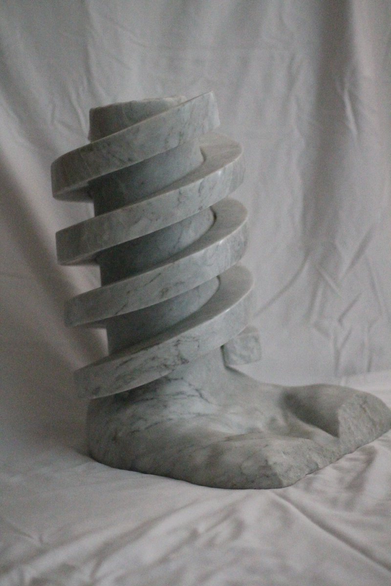 GreenGolemMag's tweet photo. “Golem DNA” by Hal Goldberg

The double helix DNA of the Golem is now preserved in marble, and will re-create a new Golem whenever the Jews are in jeopardy.  On the top of the double helix is carved the word “Emet”, “truth” in Hebrew.

In the original story of the Golem of Prague, the Golem was activated by inscribing “Emet” on its forehead. To deactivate the Golem, the letter aleph was removed, transforming the word “truth” to the word “death”.

(2001) White Carrara Marble 17" x 11" 13"

Hal has been a marble sculptor for over 50 years. He studied at the Laguna College of Art and Design (Laguna Beach, California)  and at the Art Students League (New York), but is primarily self-taught. He carves directly in the stone.

The purpose of Hal's sculptures is to make people think long and hard about the Holocaust. The sculptures are dedicated to one of the most important lessons of the Holocaust - Am Yisroel Chai - the Jewish people will always survive.