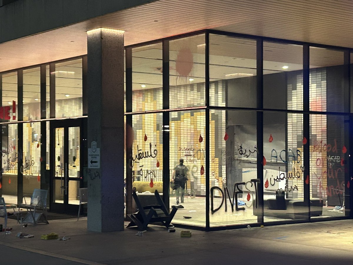 KNXBaird's tweet image. A police officer is visible inside a building at #CalStateLA that #proPalestinian protesters occupied.  At least for awhile.  They piled up overturned golf carts and tables as a makeshift barricade.  They’re gone now @knxnews