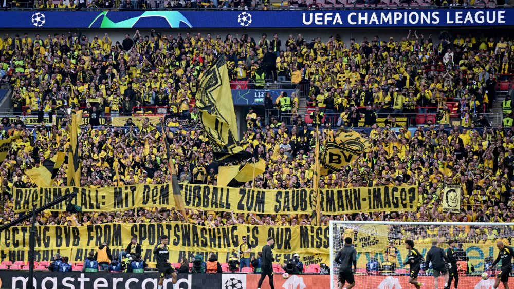 gerdwenzel's tweet photo. Em Wembley, torcida aurinegra protesta contra o patrocínio da Rheinmetall, indústria de material bélico, com duas faixas: "Rheinmetall: com futebol para criar imagem limpa?" e "Nossa missão é proteger o BVB do sportwashing" (Veja imagem) https://t.co/EdtoQmWISZ