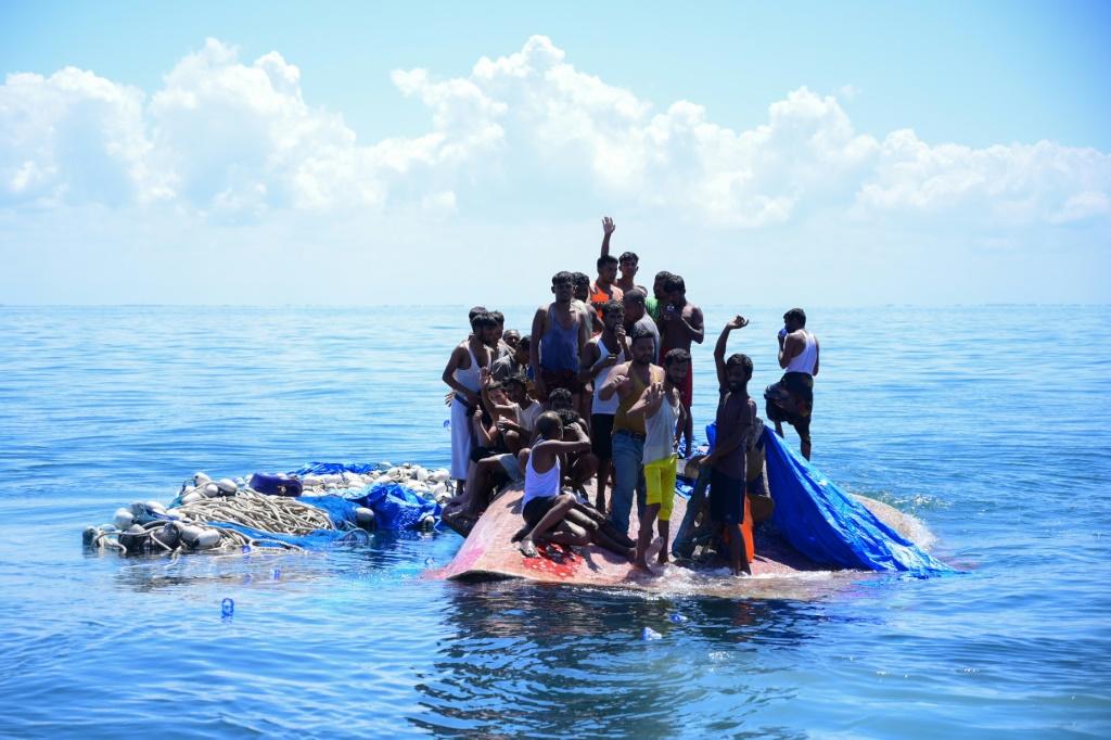 Rohingya refugees wait to be rescued from the hull of their capsized boat as a National Search and Rescue Agency vessel approaches in waters off Indonesia in March 2024 (Zahlul Akbar/AFP)