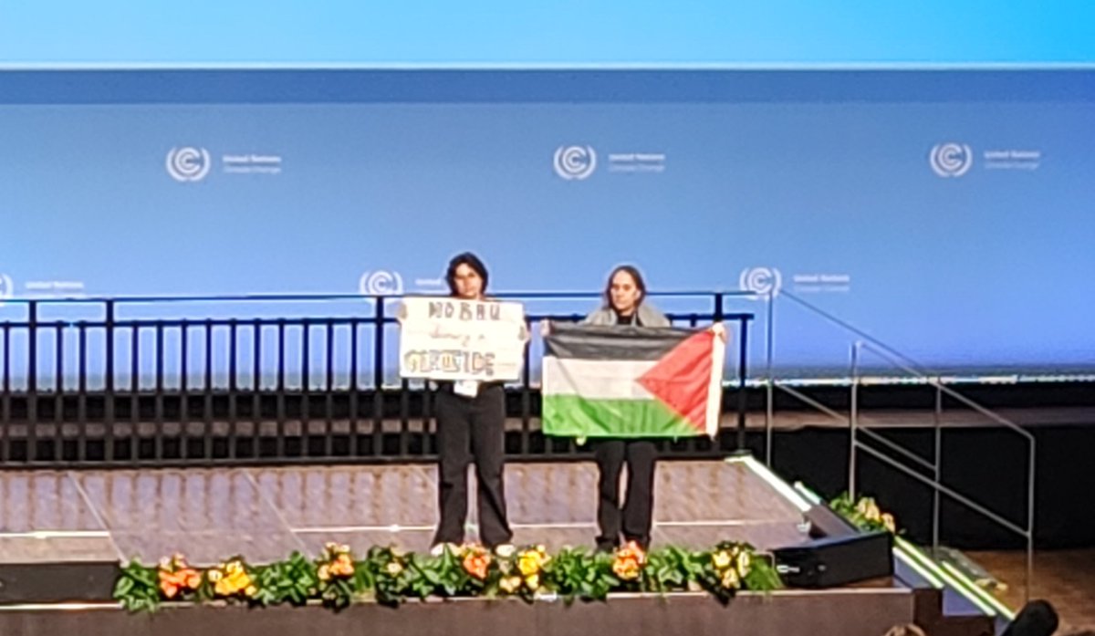 adrien4ej's tweet photo. BREAKING: Activists raised a Palestinian flag and banner that reads "No business as usual during a genocide," at opening plenary of the @UNFCCC #SB60 Climate Change negotiations in Bonn, Germany. Plenary was suspended and UN police escorted activists out the venue. #FreePalestine https://t.co/u8lvUNMzCs