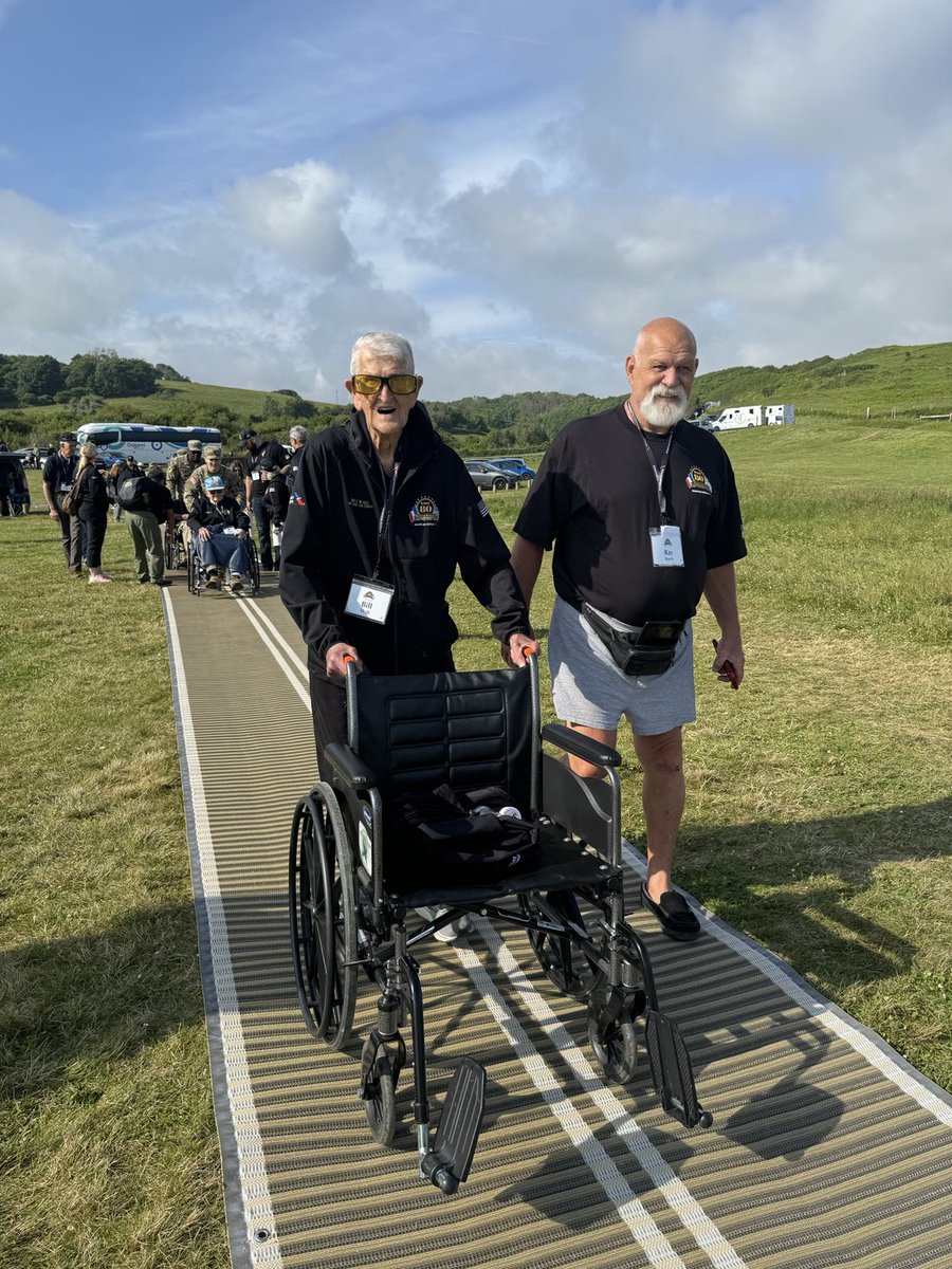 Pushing his own wheelchair: WW2 veteran Bill Wall (left) walks to a ceremony June 4 at Omaha Beach. Wall was an aerial gunner on a B-17 during more than 30 combat missions over Europe.