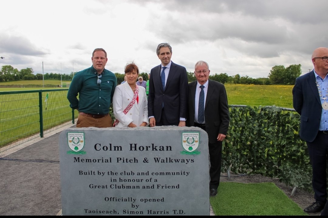 MayoGAA's tweet photo. An Taoiseach Simon Harris TD was in Mayo Sunday to official open the Colm Horkan Memorial Pitch and Community Walkways. He was joined by Minister for Justice Helen McEntee, Garda Commissioner Drew Harris, Charlestown GAA club officers players and members.  Representatives of the Mayo GAA Executice were also present. Taoiseach Simon Harris said it he was delighted to be in Charlestown as it was a day of community celebration & pride and also a day of grief at the loss of Det. Garda Horkan in the line of duty.  He said the pitch and walkways were a fitting tribute to Colm Horkan and his incredible service and impact. An Taoiseach Harris was also joined at the ceremony by Ministers of State, Dara Calleary and Alan Dillon, as well as local TDs and councillors.