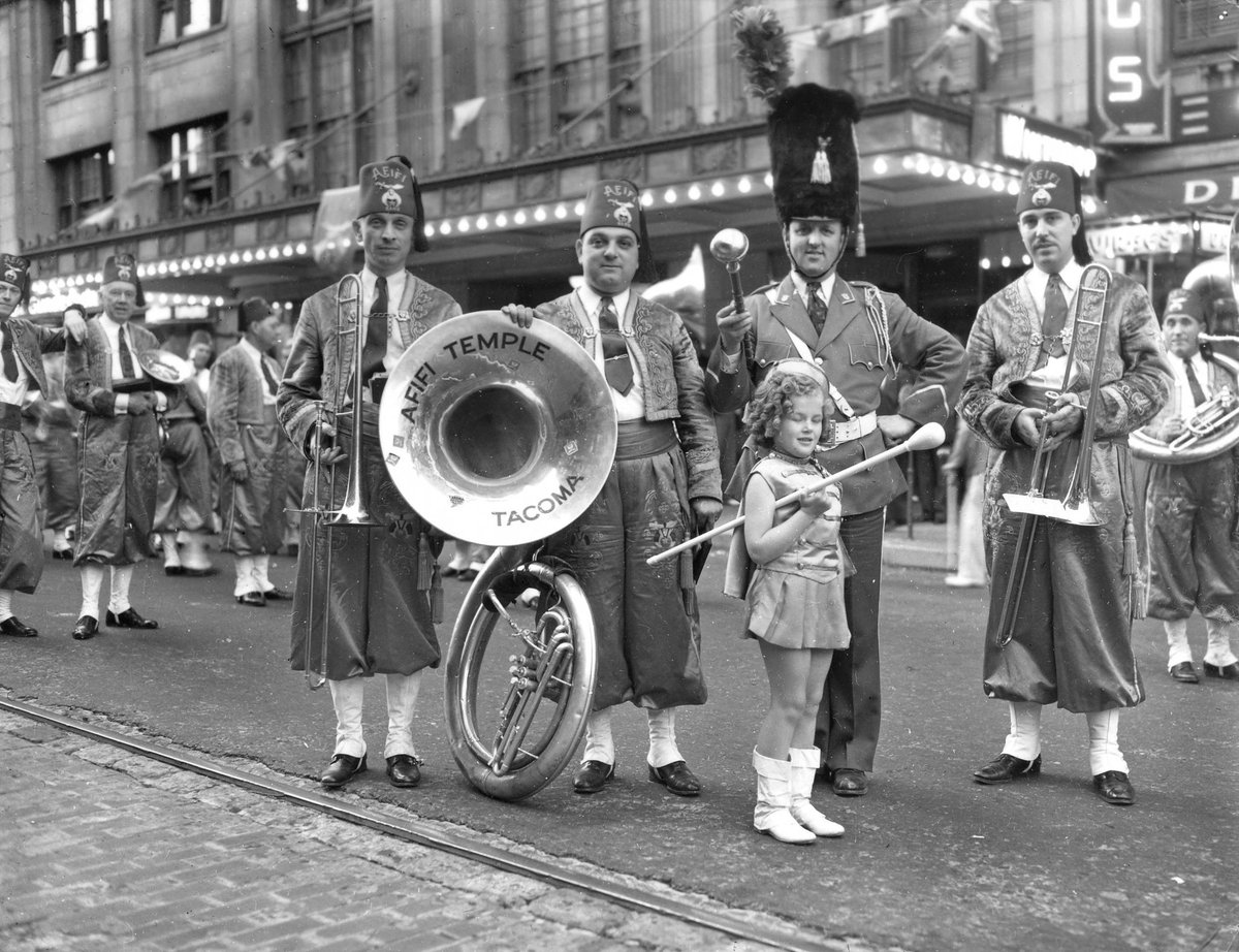 Tacoma_History's tweet photo. On Saturday, June 5, 1937, over 1,000 Shriners gathered in Tacoma for a Spring reunion sponsored by Tacoma's Afifi Temple. Afifi temple drum major Tom Richards, third from left, posed for a photograph in front of the Winthrop Hotel with "mascot" Marjorie Joy … https://t.co/aqkd4sW7c2