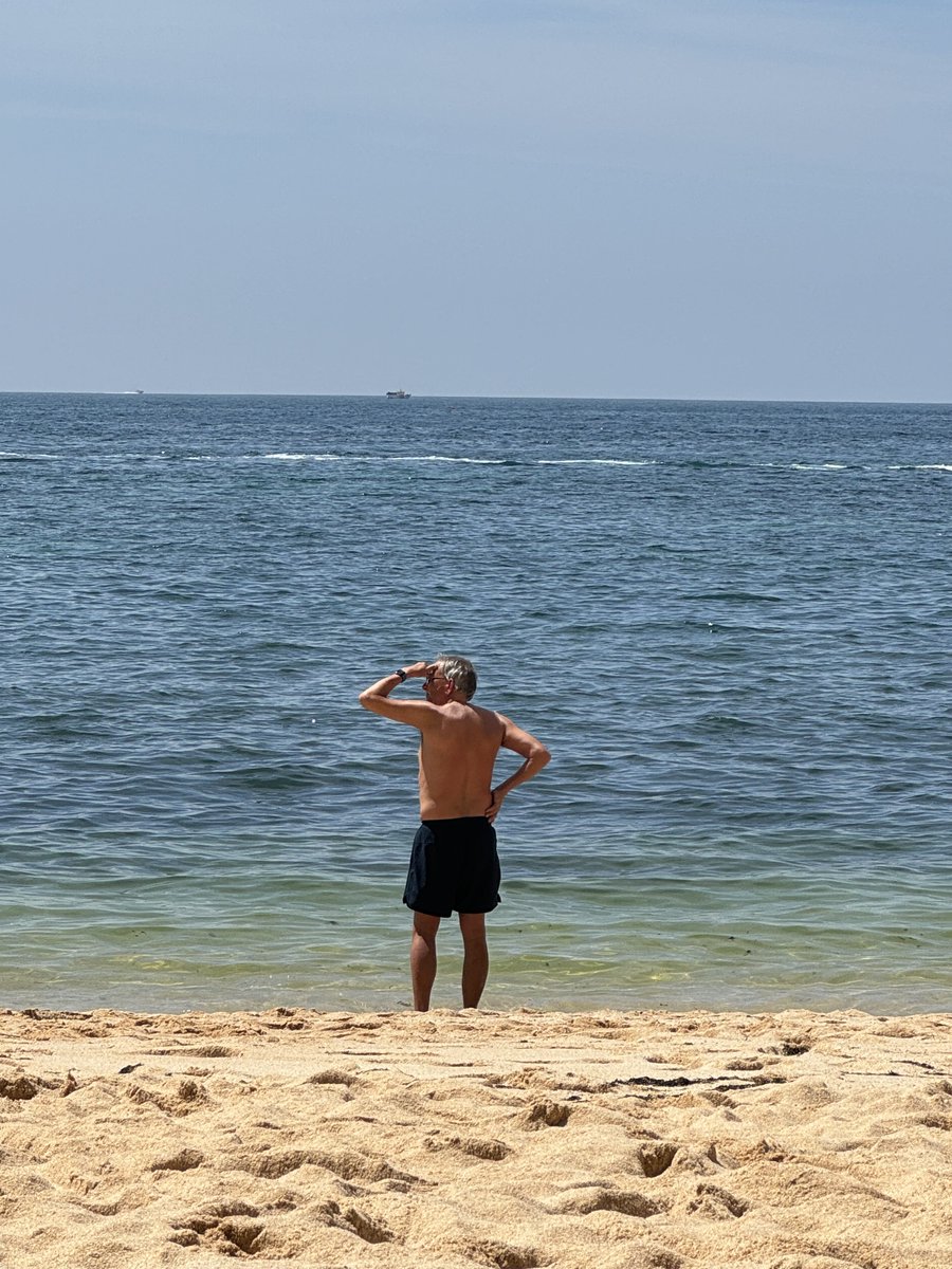 johnswart's tweet photo. Seems #JohnWanders may have forgotten something while walking along the shore of Praia da Marinha in Portugal. Oh right, his daily beach towel duties, this time on Praia dos Caneiros. ( @shwise00 photos ) https://t.co/9OAf7saOUy