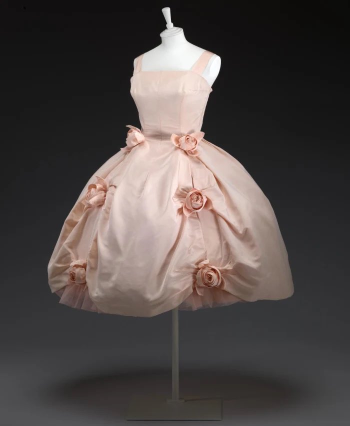 One of the earliest collections Yves Saint Laurent designed in his own right for the house of Dior in 1958 included this short crinoline style gown in soft pink. The rose theme is echoed through self coloured blooms that catch at the hem <a href="/NGVMelbourne/">NGV</a>