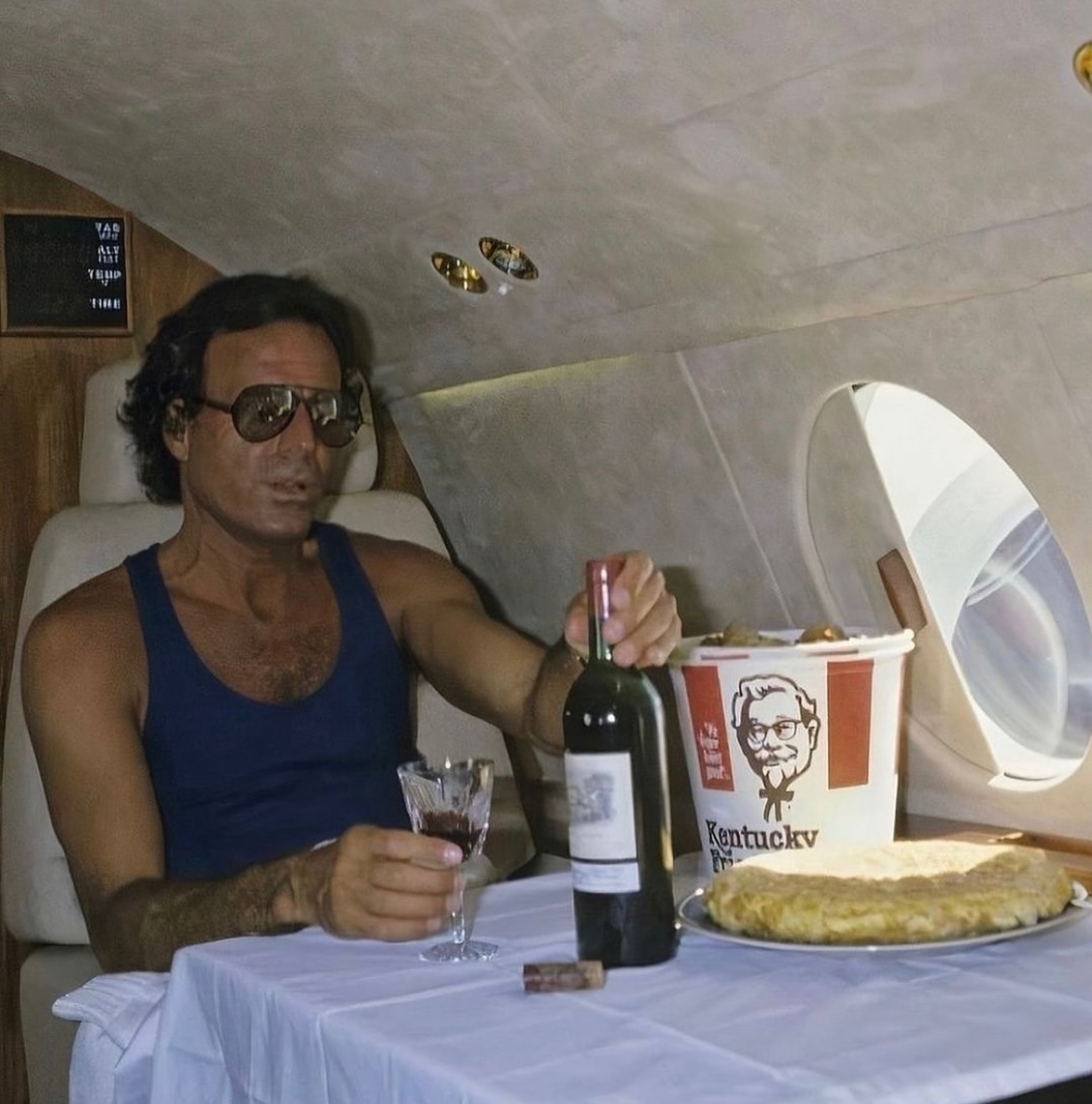 Julio Iglesias on his private jet with a bottle of wine and a bucket of KFC