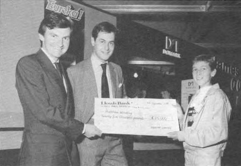 LegendsSpectrum's tweet photo. Domark's Dominic Wheatley (second from the left) and Mark Strachan (second from the right) celebrate the release of its latest game, Eureka! The glass box holds £25,000, the prize for the first person to crack the game. It was won by 15-year old Matthew Woodley. https://t.co/G0RuM6KnBQ
