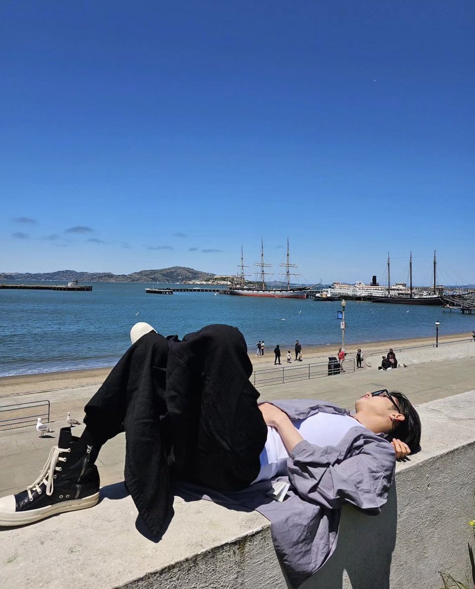 Yawnzbzn's tweet photo. Basking in the warm glow of the sun, reclines on a ledge overlooking the serene waters in San Francisco Bay. The blue sky stretches infinitely above, while the calm waves lap gently at the shore, creating a perfect harmony between the elements of nature and the calm repose. https://t.co/g1OJWoRbb2