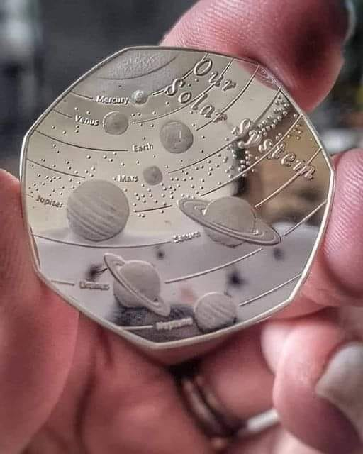 A coin (50 pence, UK, sterling) with the solar system.