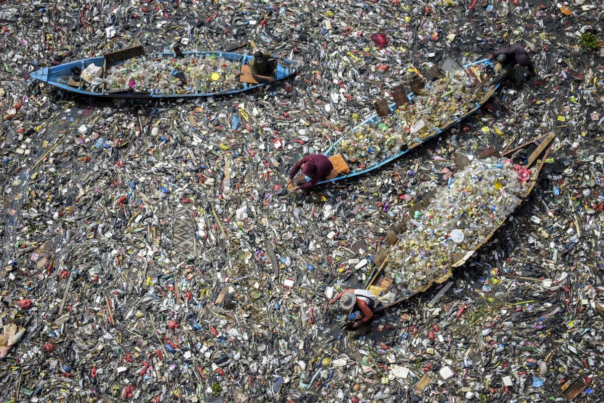 People in small boats collect recyclable plastics from the heavily polluted Citarum River in Batujajar Village in Bandung, Indonesia on 12 June 2024 (Timur Matahari/AFP)