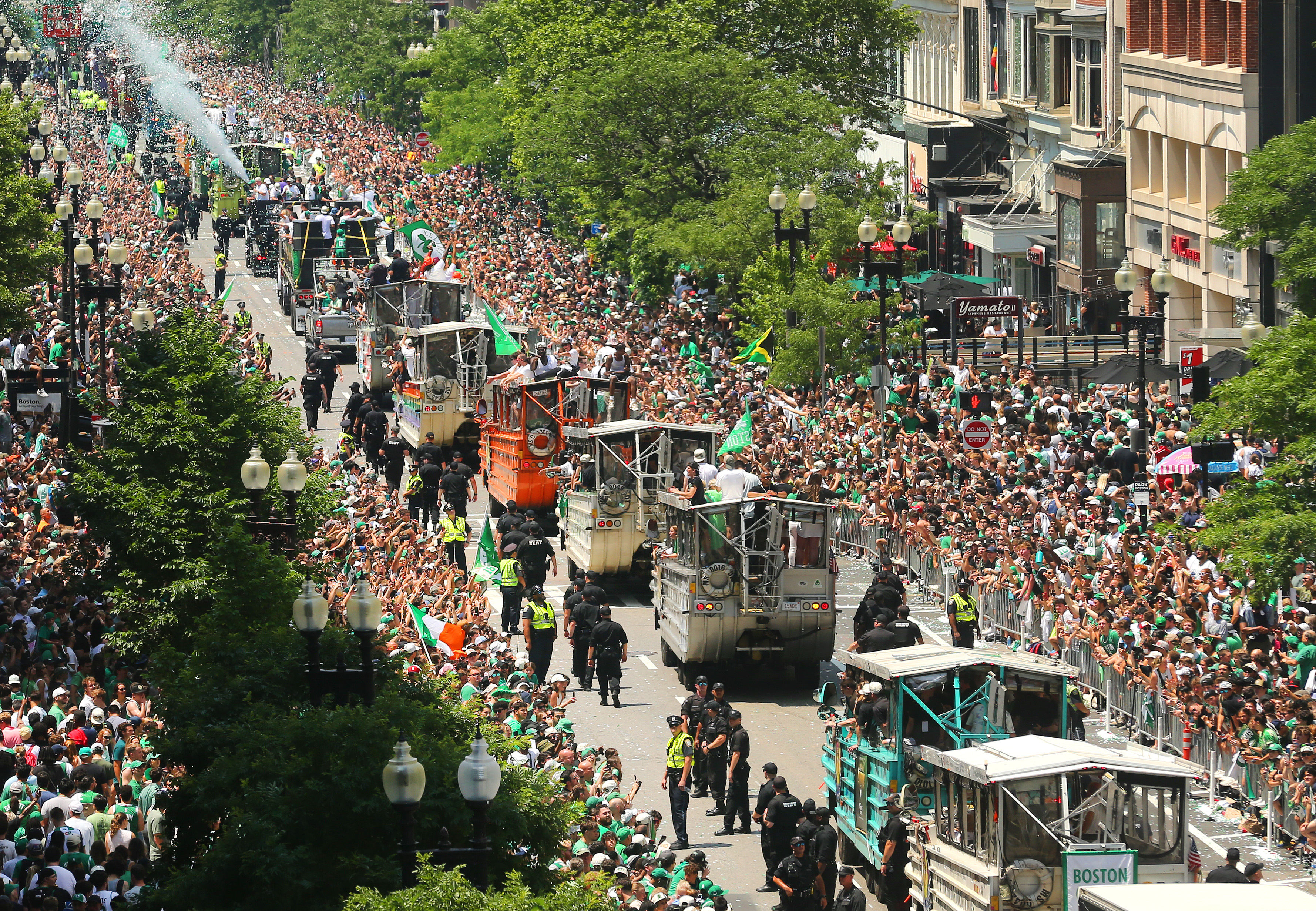 Duck boats travel down the street as crowds cheer during the parade for the 2024 NBA Champion Boston Celtics.