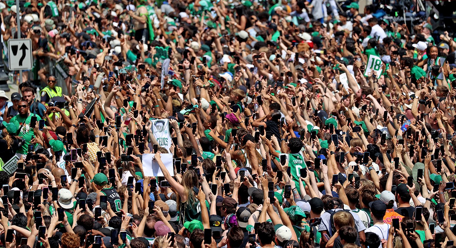 A crowd of fans cheer during the duck boat parade for the 2024 NBA Champion Boston Celtics.