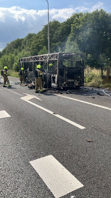 Brandweerlieden staan bij de uitgebrande bus. 