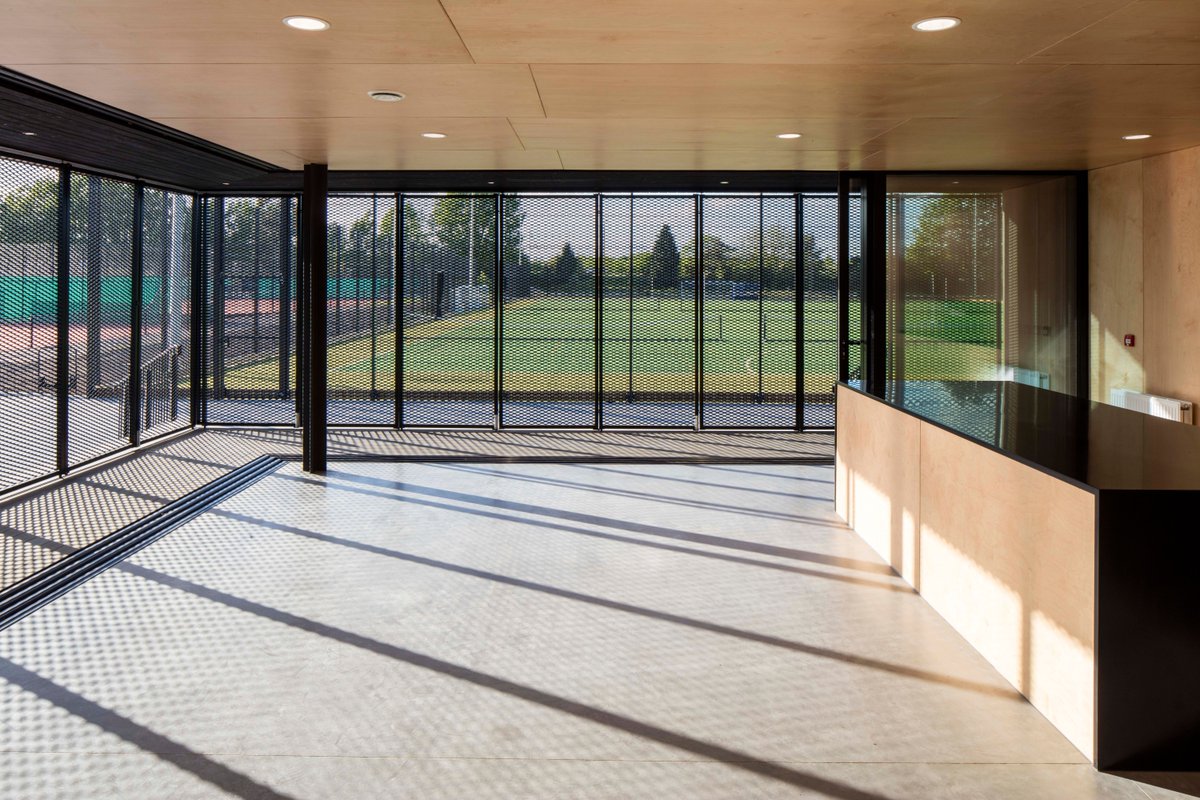 Sunlight seeping through the patterned metal screen. It beautifully wraps around the wooden core of the Willowbrook tennis pavilion, balancing enclosure and sense of openness. #beautifulsportvenue #summertime #morninglight #elegantpavilion  #architecture #detaildesign