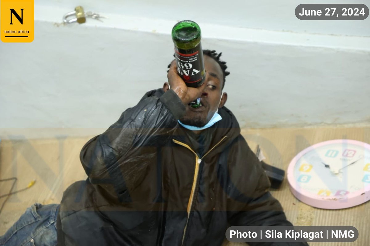 Suspected looter held by police at Clean Shelf Supermarket in Ongata Rongai drinks alcohol found in his possession