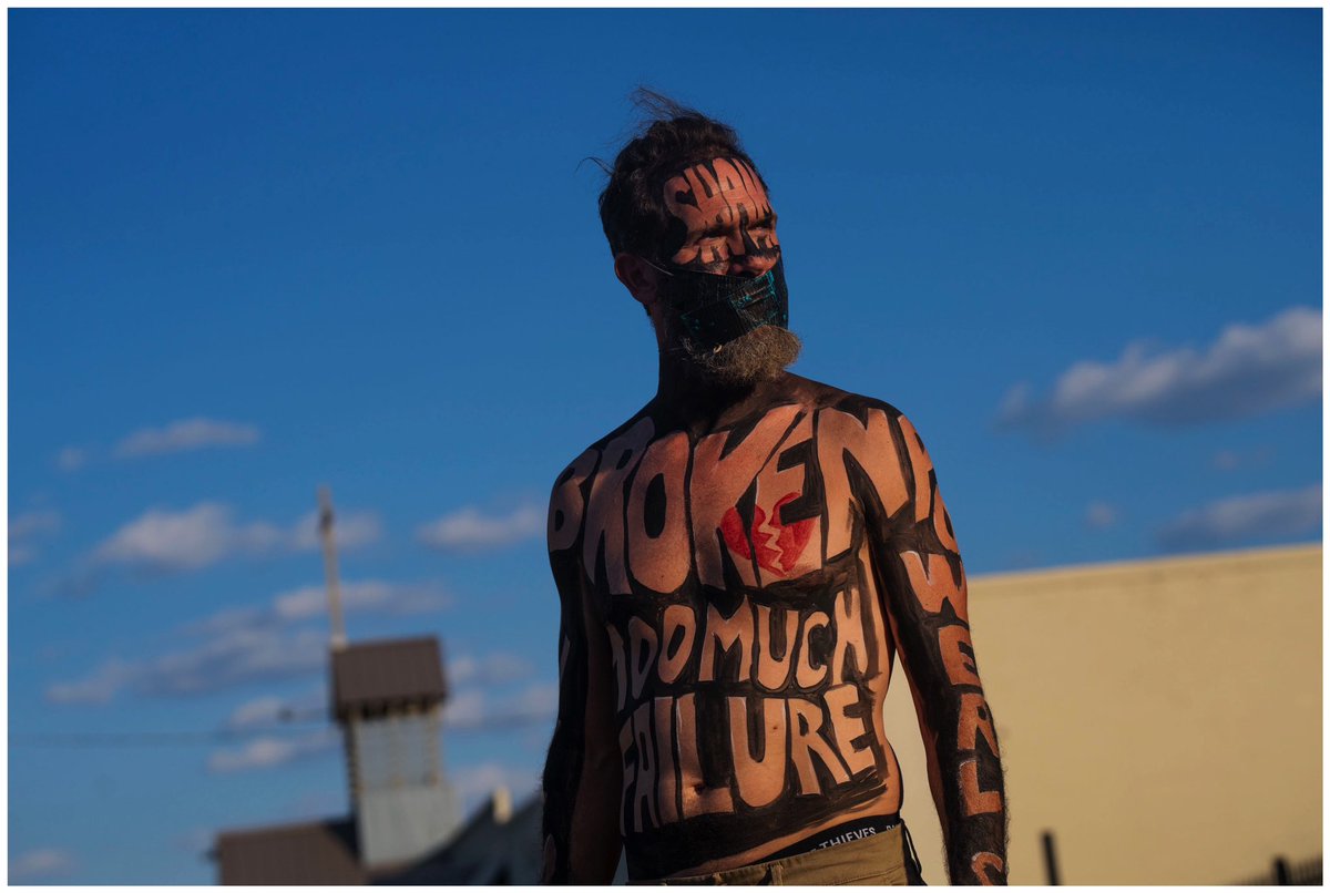 The man stood quietly on the sidewalk outside the Greater Grace World Outreach complex in East Baltimore on Monday night. He was barefoot and shirtless, with two pieces of duct tape covering his mouth. There were words painted on his face, arms, legs and torso, and across his