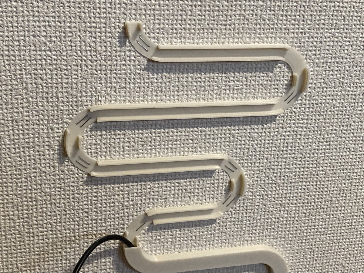 nkitani's tweet image. 3Dプリンターでスマート家電コントローラ(ラトックシステム RS-WFIREX3)の壁掛けホルダーと配線モールを作りました。市販のモールでL字に配線するよりもケーブルの存在感が薄れるかな〜?って思ってクネクネさせてアートっぽくしてみた。壁面固定はASAフィラメント0.4mm厚の底面をホッチキスで。