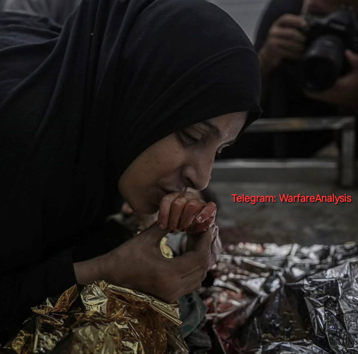 warfareanalysis's tweet photo. A Palestinian mother kisses the hand of her daughter who was murdered by an Israeli bombing of their home in Bureij camp, central Gaza 

[G&amp;T] https://t.co/xONztEgJf9