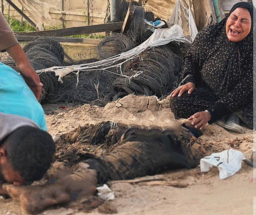 A woman crying and a young man accepts what is left of his father's body.