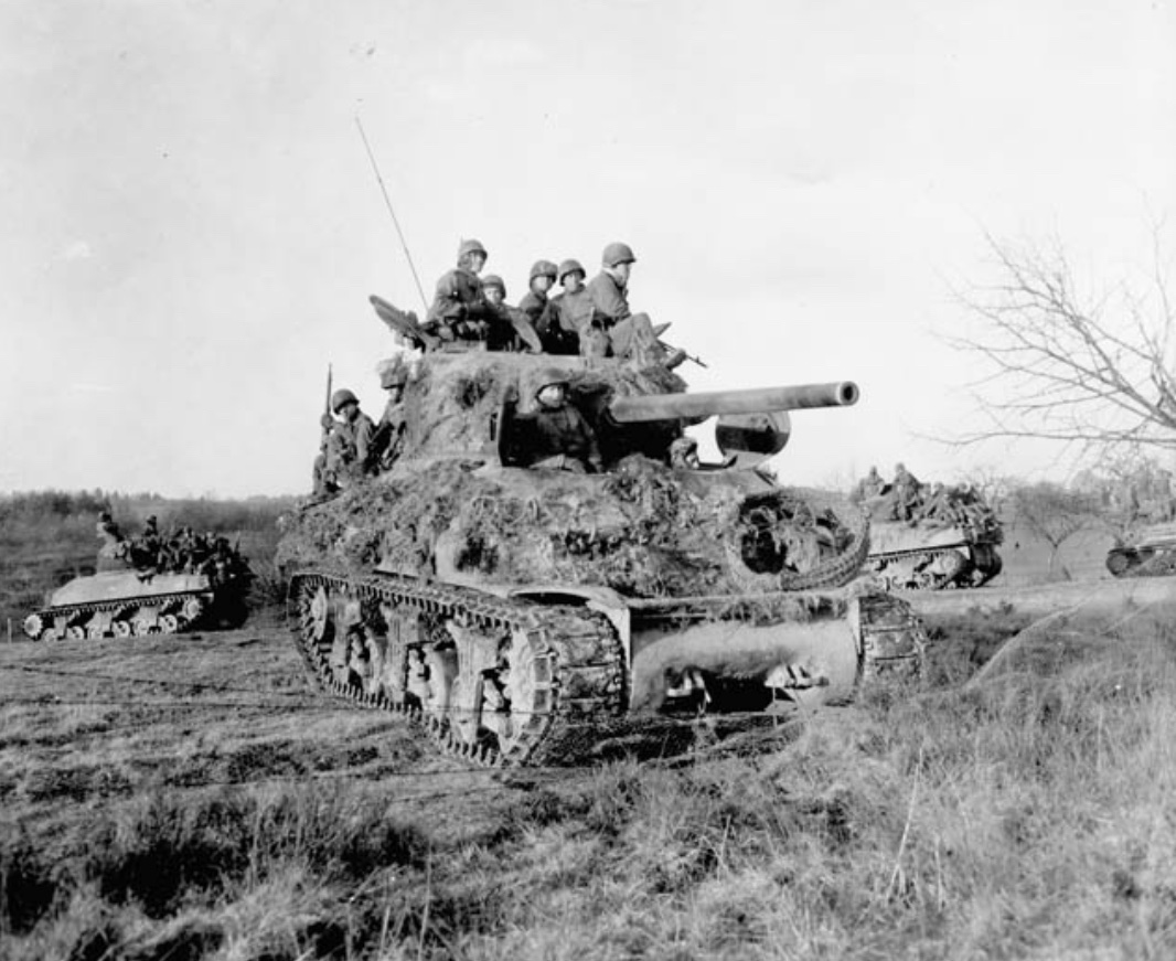 In December of 1944, Infantrymen ride into battle atop a ...