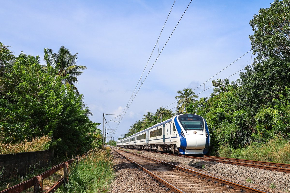 8 car Thiruvananthapuram Central bound Vande Bharat Express rolling down a gradient through lush green Kappil