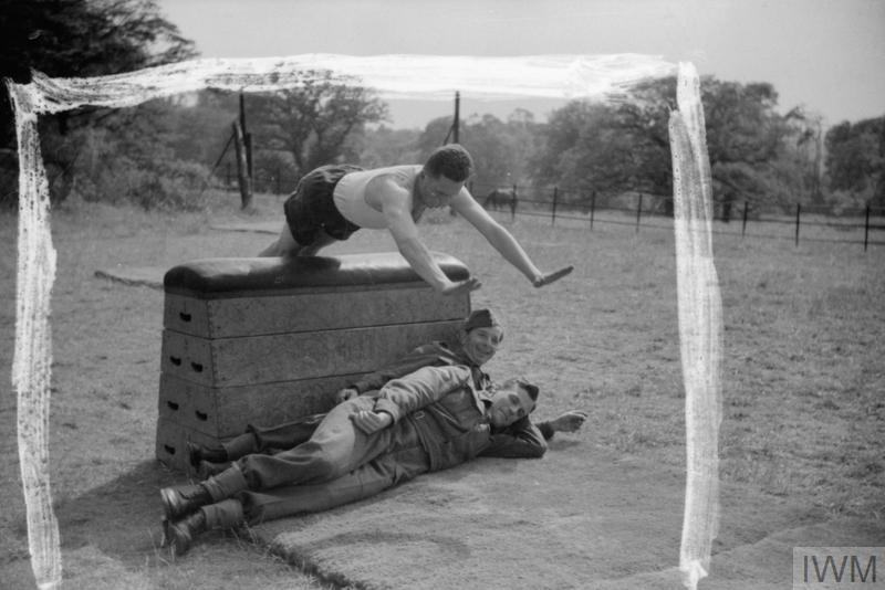 A Belgian paratrooper does 'flying angel' jumps over a wooden horse as part of his 'limbering up exercises during parachute training at Ringway, near Manchester, 1942. 

IWM (D 8696)