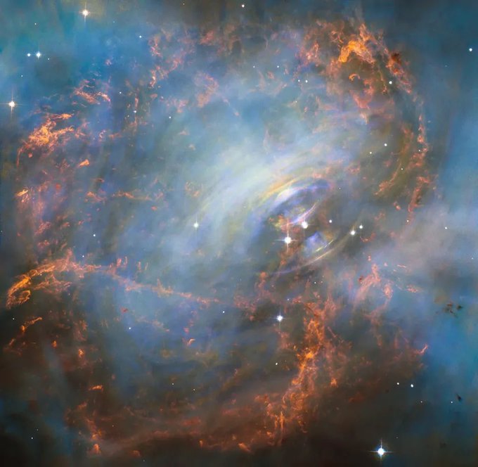 The Crab Nebula glows in blue and orange hues. At its heart is a pulsar, which is a rapidly spinning, collapsed core of a star.