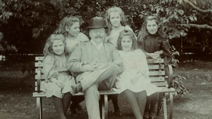 Photo of Dr Barnardo sat on a bench with five children