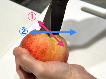 桃のヘタ（上）側に十字の切れ込みを入れているところです。