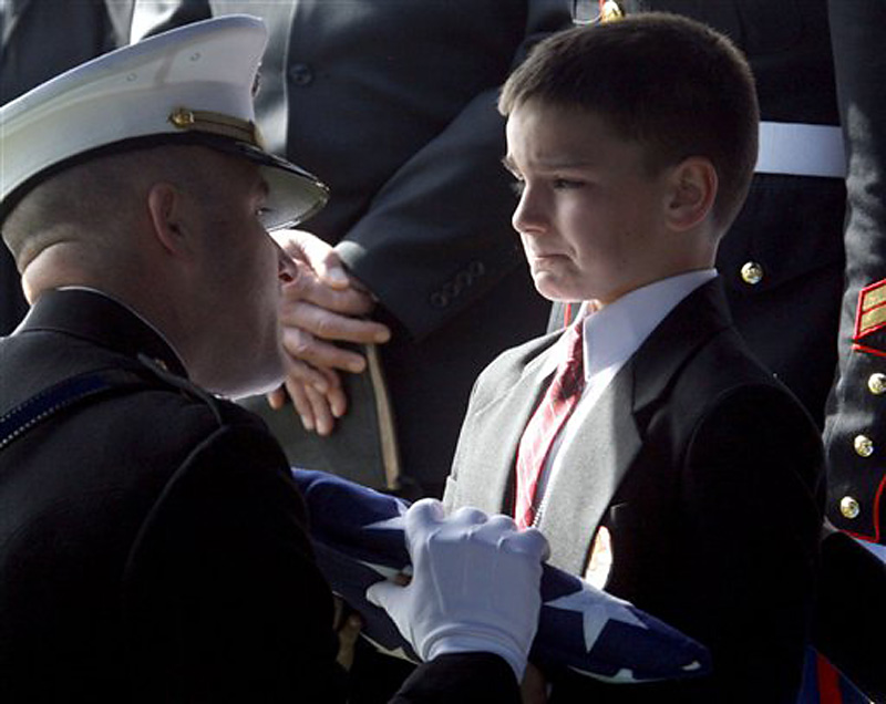 4. An 8-year-old, his lip trembling, is handed a folded flag at his father's funeral.