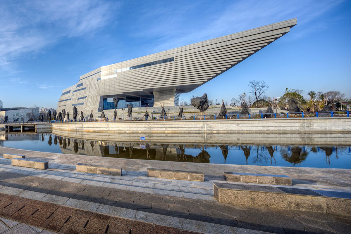lexurbangroup's tweet photo. El Museo del Centro Cultural de Qujing China. Diseño Atelier Alter+Hordor Design Group. Techo "antigravedad secciones estructurales escalonadas parece flotar. Los muros exteriores: paneles de hormigón con metálicos verticales y losas de pavimento gris 
#MuseoCentroCulturalQujing https://t.co/4oqdlzmr49