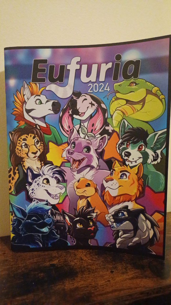 Eufuria convention book cover by Royalty. Fursonas of SCREE Inc. staff members surrounding Joy.