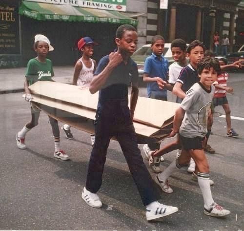 Kids carrying cardboard for breakdancing, NYC, 1983.