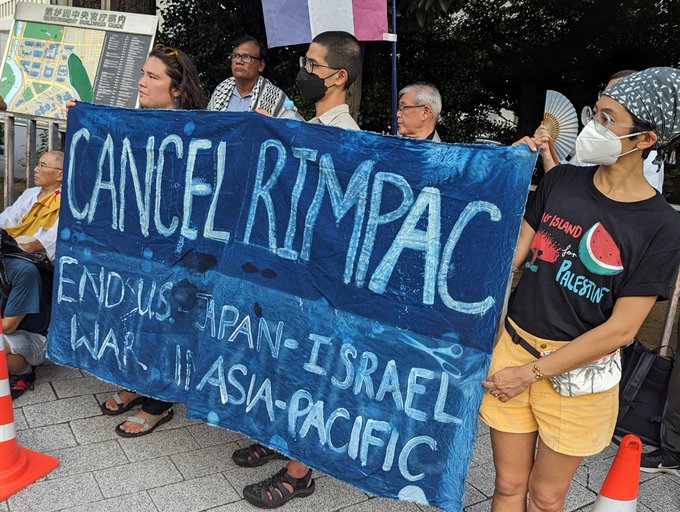 7月19日、官邸前でのパレスチナ連帯アクションで掲げられた「CANCEL RIMPAC」（リムパック=環太平洋合同軍事演習をやめよ）の横断幕を掲げる人々。