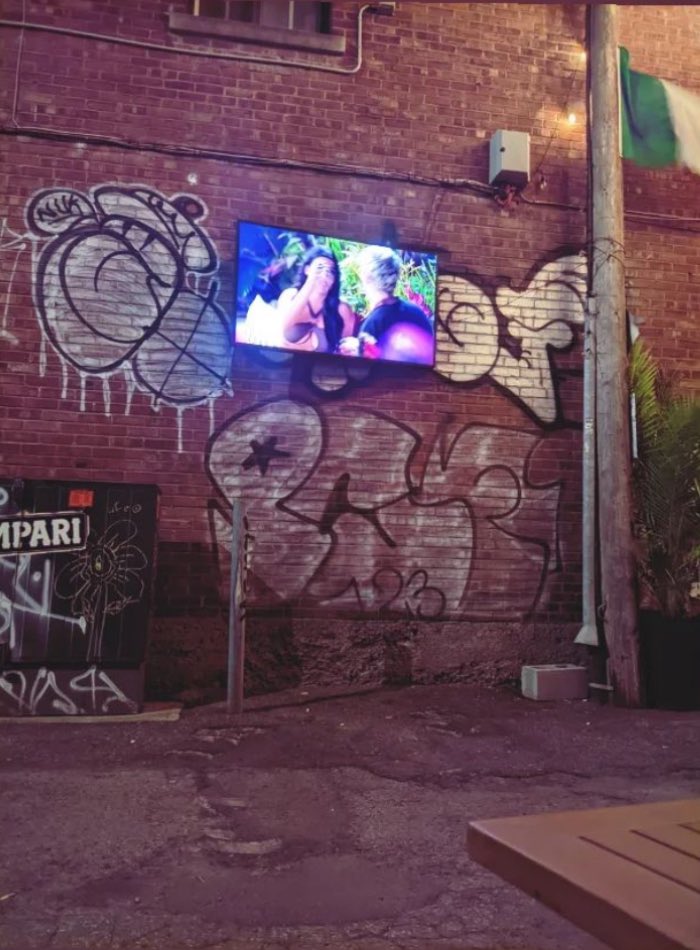 HotCommieWife's tweet photo. Save me, Love Is Blind on the tv of the outdoor alley café patio. Save me. https://t.co/se9sVBoEwI