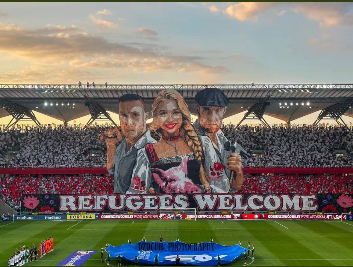 TRobinsonNewEra's tweet photo. In response to a soldier being killed by migrants at their border, Legia Warsaw unveil "refugees welcome" banner today depicting Polish men with a hammer and a baseball bat and a woman holding a pigs head.

Chants of: "All of Poland sings with us, fuck off with the refugees." https://t.co/nV0BkxsBg7