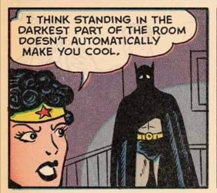 a comic panel featuring wonder woman and batman. there is a dialogue bubble coming from wonder woman that says "i think standing in the darkest part of the room doesn't automatically make you cool." batman is shown in the background looking sad.