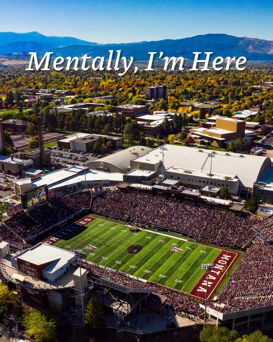 The words “mentally, I’m here” over a picture of the University of Montana’s football stadium with Missoula in the background.