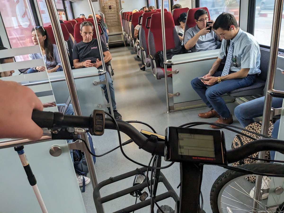 BikeLaneSpencer's tweet photo. I am currently taking a train with an E-bike to attend an Urban Transportation Commission meeting, in a building that used to be a parking lot of an abandoned mall.

Have I achieved peak urbanism? https://t.co/4mmy2H9DJa