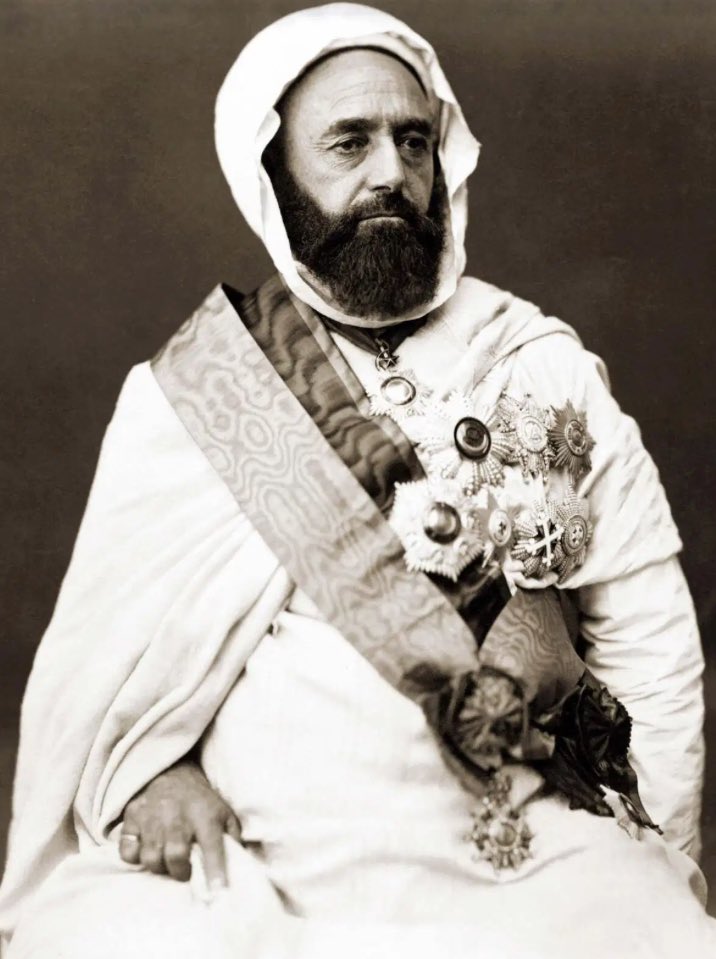 UnionNatioPop's tweet photo. Ça c’est Abdelkader ibn Muhieddine.

Abdelkader c’est avant tout une jeunesse dans une famille aristocratique des environs de Mascara. Si l’on devait trouver son équivalent européen, ce serait un duc. Son père est très actif au sein des institutions religieuses, sa mère sait lire et écrire était apparemment savante en religion.

Abdelkader c’est également le studieux, bon élève, il reçoit l’éducation classique des jeunes nobles de la Régence, c’est-à-dire les maths, la grammaire, le droit, et la théologie. C’est un bon orateur et un poète relativement doué.

Abdelkader c’est aussi le résistant faisant face à l’arrivée des Français, il commence par mener des petits raids de harcèlement il a alors à peine 23 ans.

Abdelkader c’est également le fin politique, comprenant qu’il est vital de fédérer les tribus, face aux Turcs qui veulent se faire reconnaître dans le Constantinois et les Marocains qui veulent se faire reconnaître à l’Ouest, il ménage alors la chèvre et le chou sans rien reconnaître.

Abdelkader c’est aussi la ruse, sans véritables appuis c’est son courage qui finira par amener les soutiens à sa cause, et pousseront les Français à négocier, ainsi il parviendra à gouverner une vaste partie de Algérie actuelle sans verser de tribut.

Abdelkader c’est le chevalier des temps modernes, il fera ainsi libérer les prisonniers français qu’il ne peut pas nourrir, et traitera avec civilité les autres, sans les tuer.

Abdelkader c’est aussi le prisonnier, finalement défait après 15 ans de lutte acharnée, il est envoyé en France. Émir respecté de ses ennemis, on lui donne ses quartiers dans le château d’Amboise où il est assigné à résidence.

Abdelkader c’est aussi les amitiés inattendues, Louis Napoléon Bonaparte futur Napoléon III, souhaite rompre avec la politique menée par ses prédécesseurs, il le rencontre et les deux hommes s’entretiennent seuls, durant une heure. 

Abdelkader c’est le mystérieux, personne ne sait ce qu’ils se diront avec Louis Napoléon, mais ils seront inséparables par la suite, Abdelkader est libéré, reçoit une pension annuelle de 100 000 francs, une fortune pour l’époque et peu se rendre en Orient, ce qu’il voulait depuis 1847, et continuera toute sa vie à entretenir une correspondance plus qu’assidue avec Napoléon III qui le consulte pour toute sa politique orientale.

Abdelkader c’est également le juste, il empêchera le massacre de 12 000 chrétiens à Damas avec l’aide de ses fils les accueillant dans sa propre maison au besoin.

Abdelkader c’est également la fidélité, il enverra ainsi balader violemment notre verrat de concours primé de 112 kilos qui finira rongé par la gangrène et les hémorroïdes, le bien nommé Otto Von Bismarck à la veille de la guerre franco-prussienne à qui il transmet son souhait de voir l’armée française rentrer dans Berlin. Les hommes avaient la parole.

Abdelkader c’est également la tristesse, apprenant la défaite de Napoléon III face à la Prusse, il restera isolé dans la prière plusieurs jours à l’annonce de la déchéance de l’Empereur.

Abdelkader c’est l’égarement, craignant la colonisation prussienne de l’Algérie il se rangera à la fin de sa vie plus encore du côté français, reniant l’un de ses fils qui participera à la révolte des Mokranis dont le décret Crémieux et des troubles frumentaires furent deux extraordinaires aphrodisiaques.

Abdelkader a fait ce qu’il pouvait, et comme il pouvait dans des situations extrêmement complexes. Excellence, reposez en paix 🫡