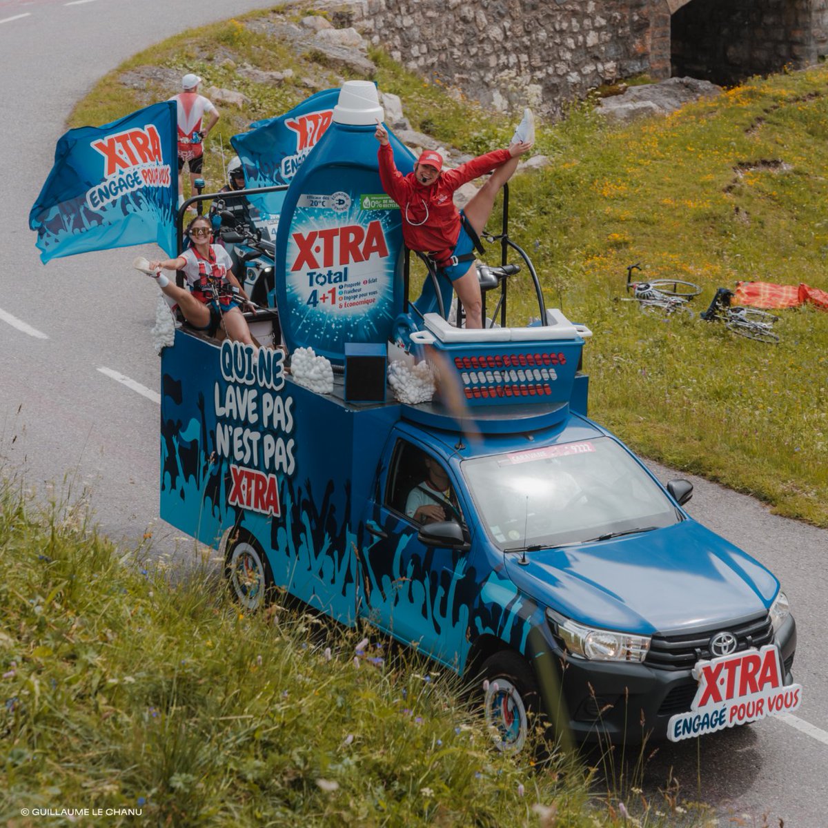 Henkel's tweet photo. For 18 years, the Henkel France #XTRA brand has been riding alongside the cycling teams and spectators of the #TourDeFrance. 🚴♀️ As the athletes breeze past, 5 vehicles shaped like #LaundryBaskets & #LaundryDetergent bottles follow, showering spectators with 405,000 goodies. 🫧 https://t.co/UmA0CklEpf