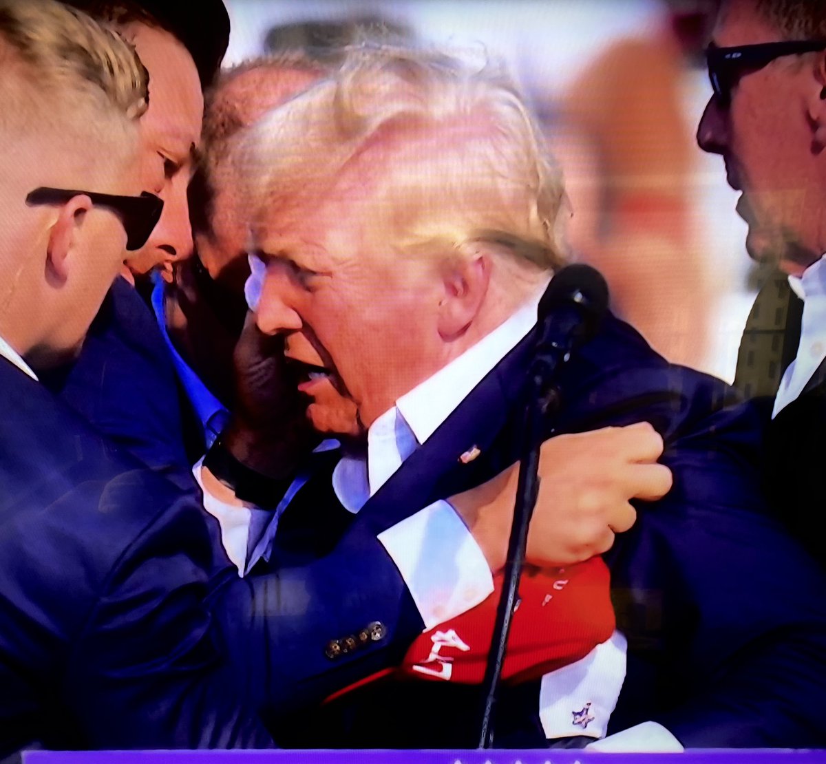 BenSwann_'s tweet photo. Absolutely Incredible: gunman attempts to shoot President Trump at his Pennsylvania rally today. Last one before the RNC convention. Trump was graced by the bullet shot directly at his face. Bloodied, the former President stood and pumped his fist in the air, shouting the word “Fight!”. President is reportedly safe and doing fine. #Trump2024